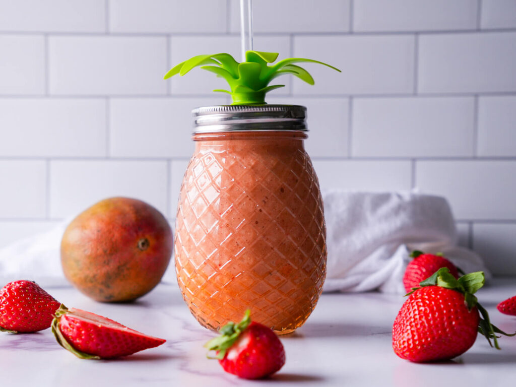 Photo of a strawberry mango smoothie in a pineapple shaped mason jar