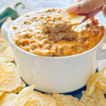 action photo of scooping Sausage Cheese Dip with a tortilla chip in a white bowl