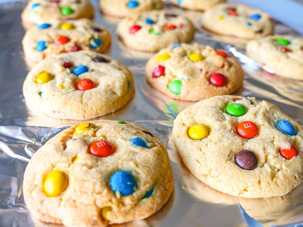 close up photo of M&M cookies on a tray of aluminum foil