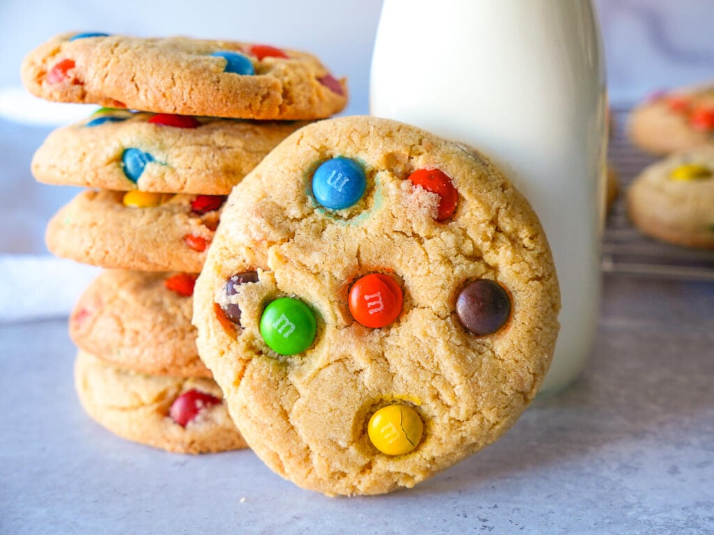 close up photo of M&M cookies stacked and one cookie standing up in the front