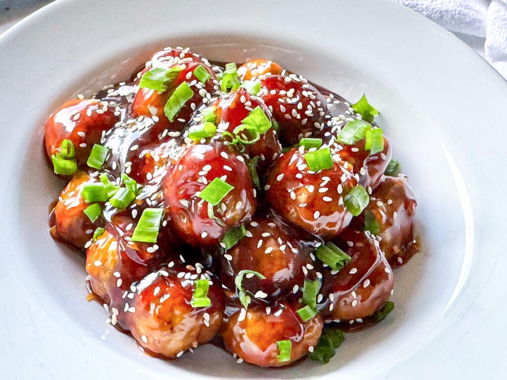 overhead photo of Honey Garlic Meatballs with green onions and sesame seeds