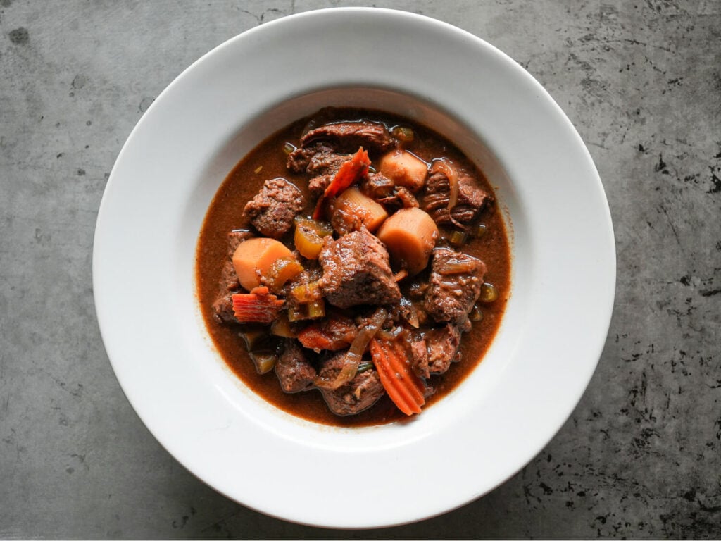 overhead photo of Slow Cooker Beef Stew in a white bowl on a metal surface