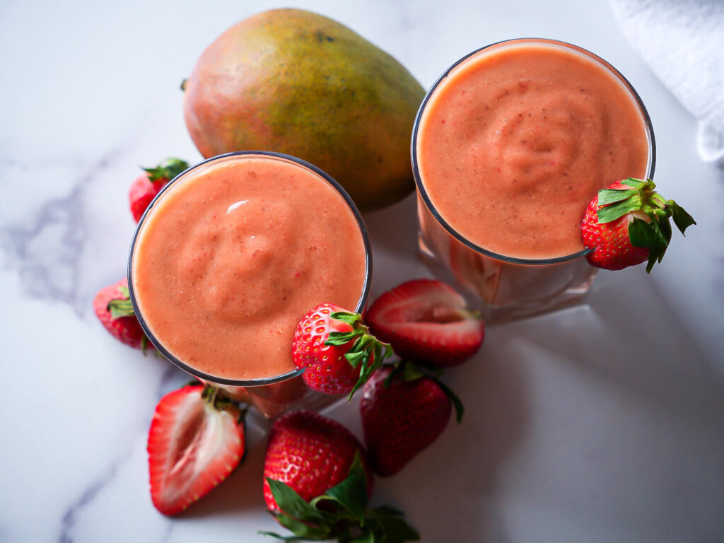 overhead photo of two strawberry mango smoothies garnished with strawberries
