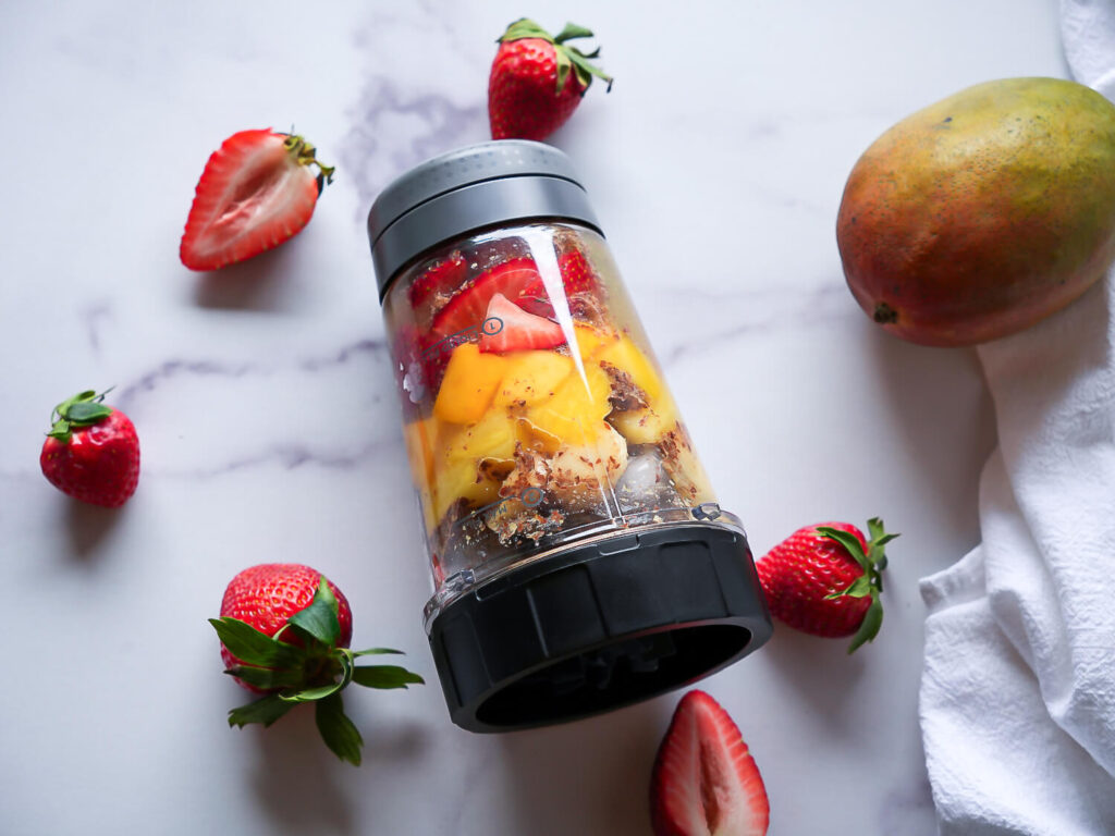 overhead shot of all ingredients in a blender bottle on a marble surface