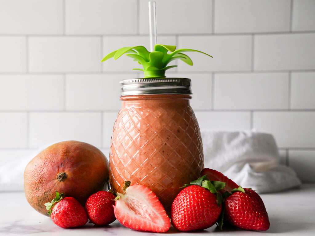 photo of a strawberry mango smoothie in pineapple shaped mason jar