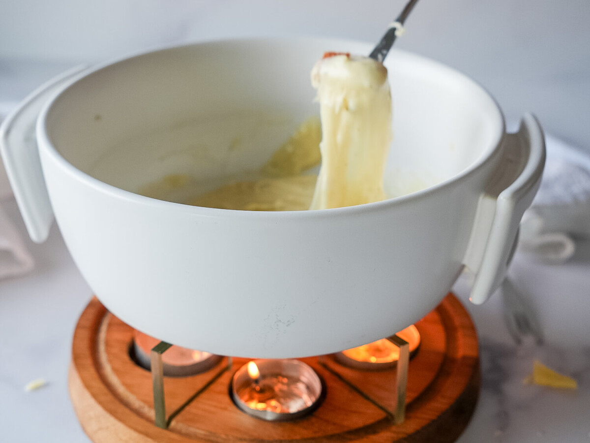 photo of bread being dipped in cheese fondue