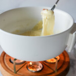 photo of bread being dipped in cheese fondue