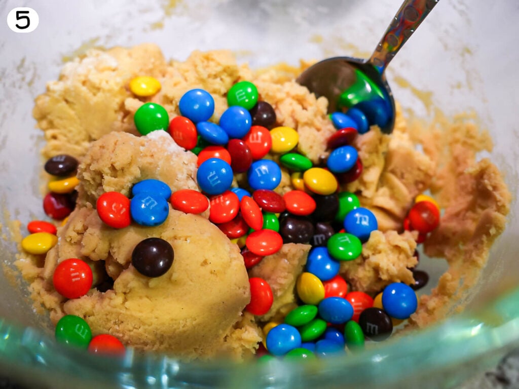 step 5 photo showing M&Ms being folded into cookie dough mixture