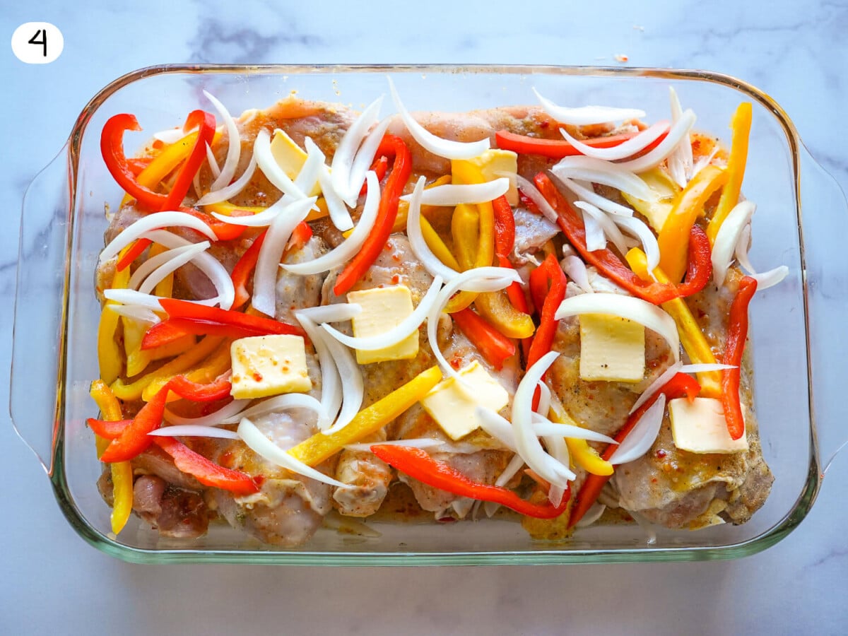 Photo of Italian Dressing Chicken in a glass baking dish with onions peppers and butter on top