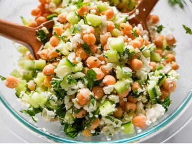 close up photo of Chickpea Cucumber Salad in a glass bowl thats tossed together