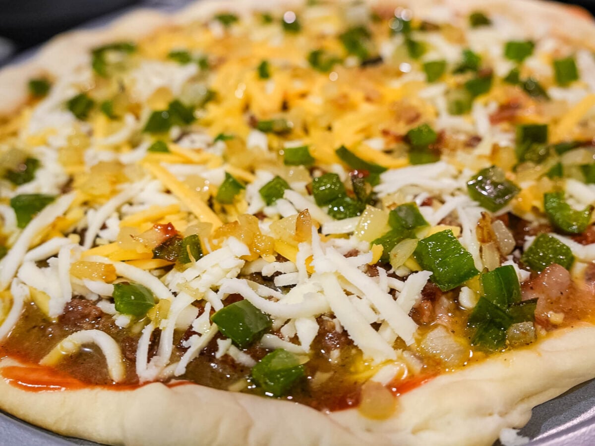 close up photo of breakfast pizza before its baked