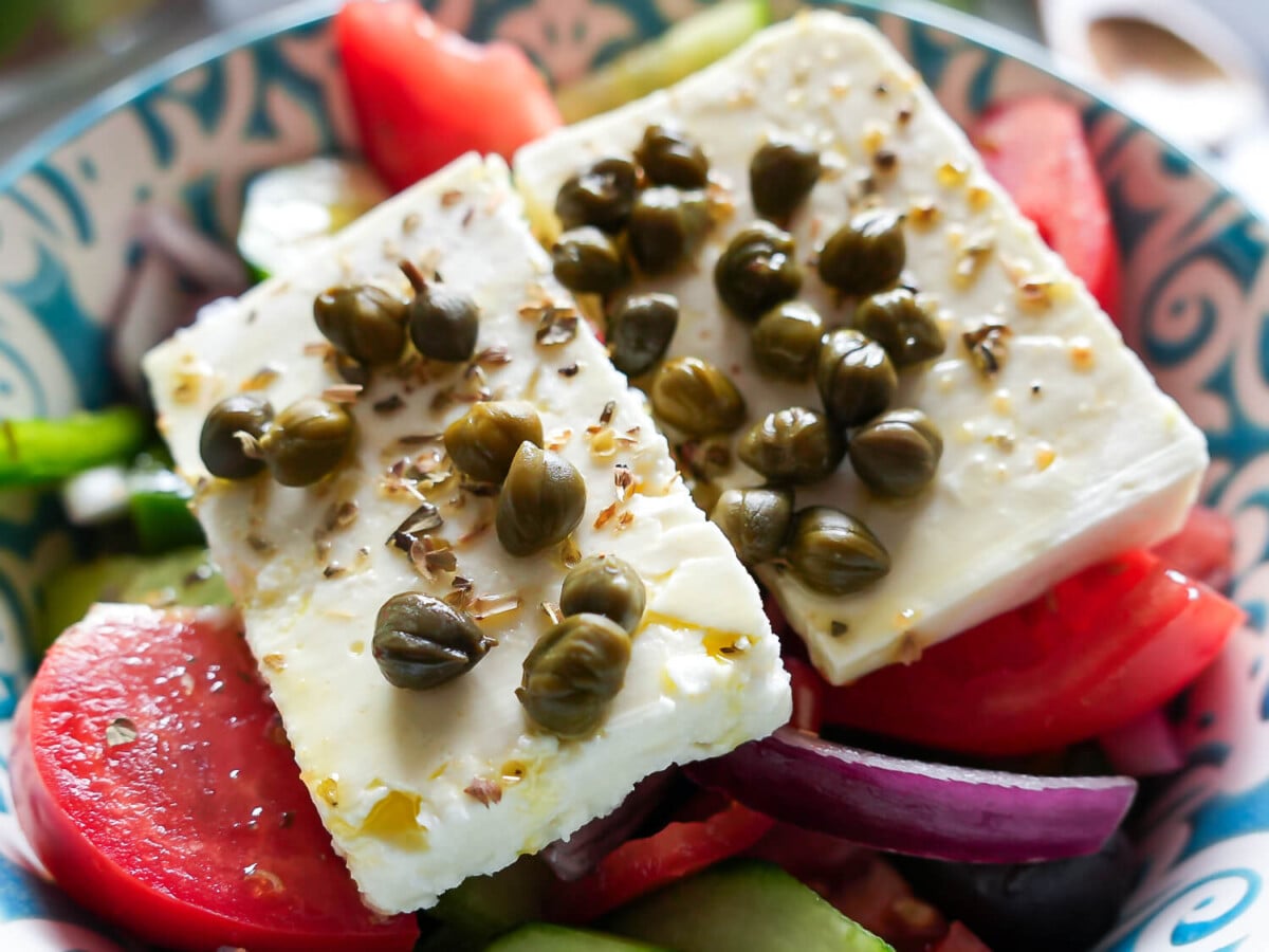close up photo of sliced feta and capers on a greek salad