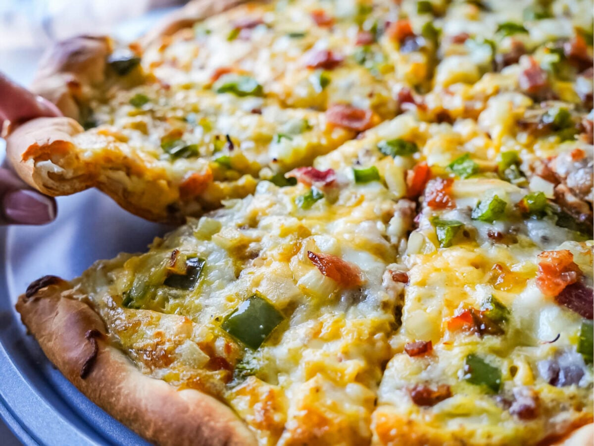 close up photo of someone pulling a slice of breakfast pizza