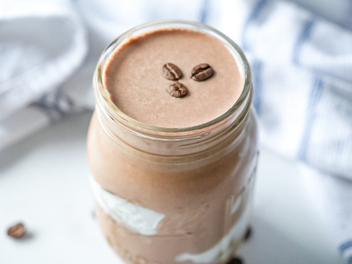 overhead photo of a coffee smoothie with coffee beans on top