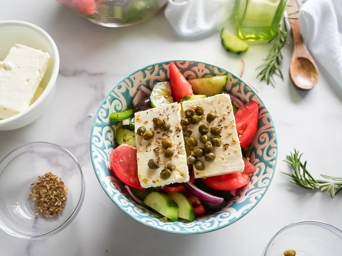 overhead photo of a greek salad in a blue and white bowl