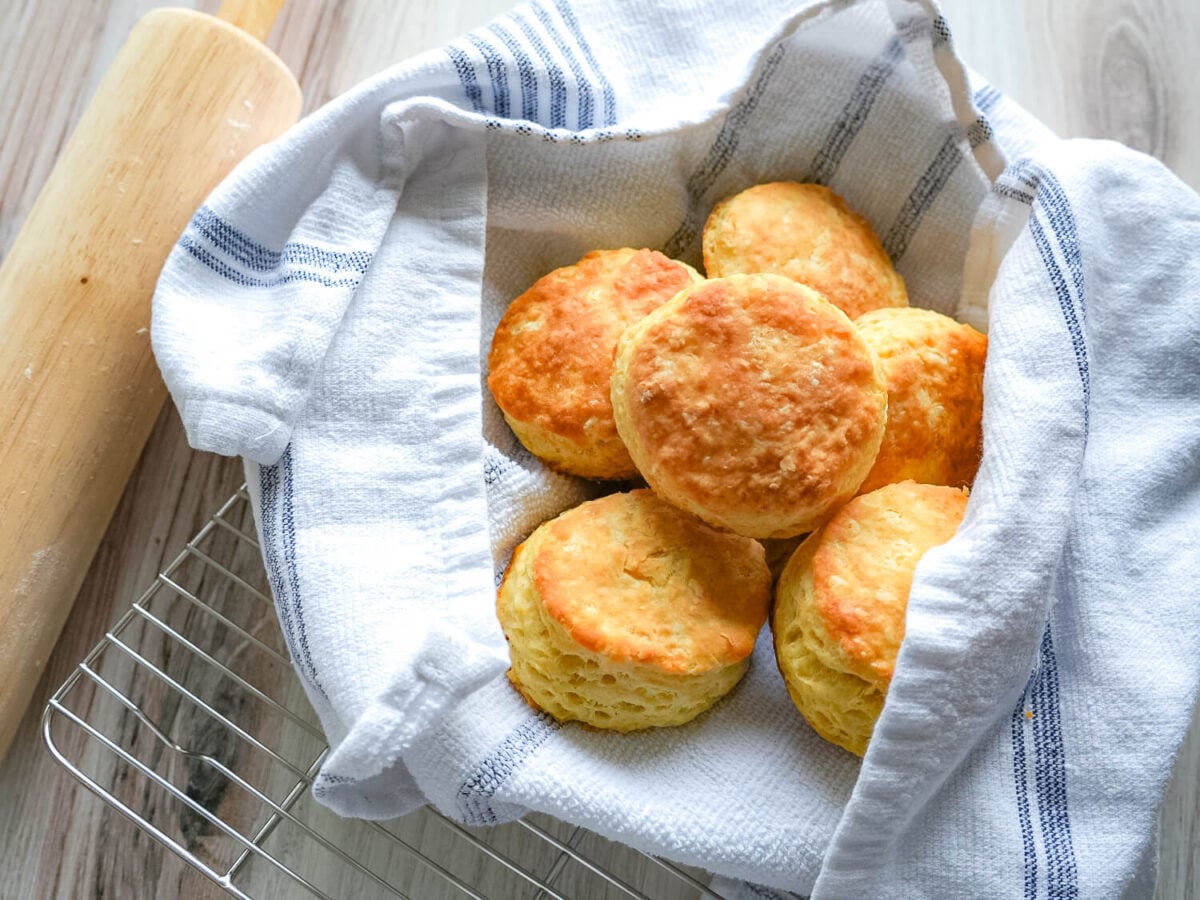 photo of buttermilk biscuits wrapped in a towel next to a rolling pin