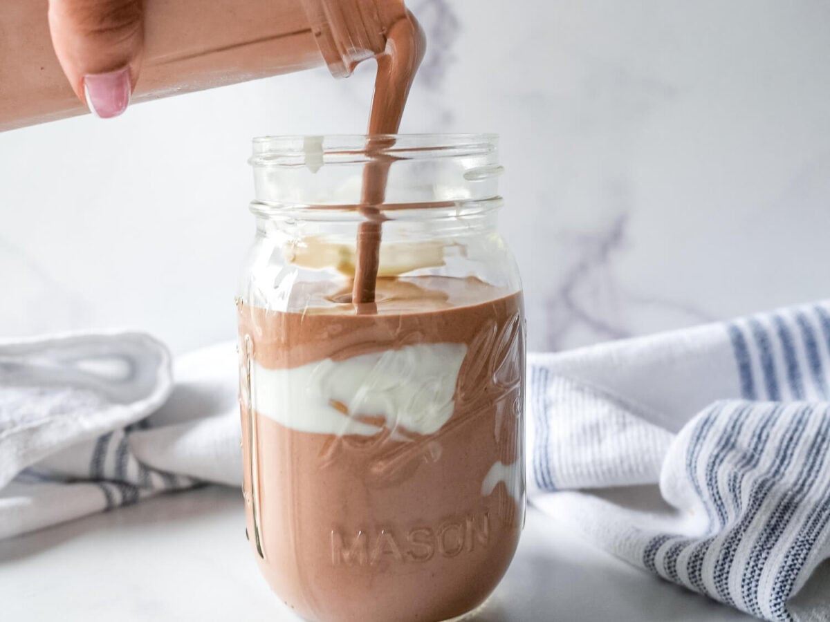 photo of coffee smoothie being poured into a mason jar from a blender cup