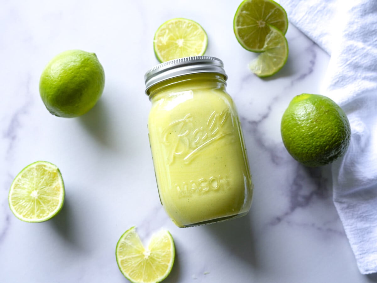 photo of lime curd in a mason jar surrounded by limes