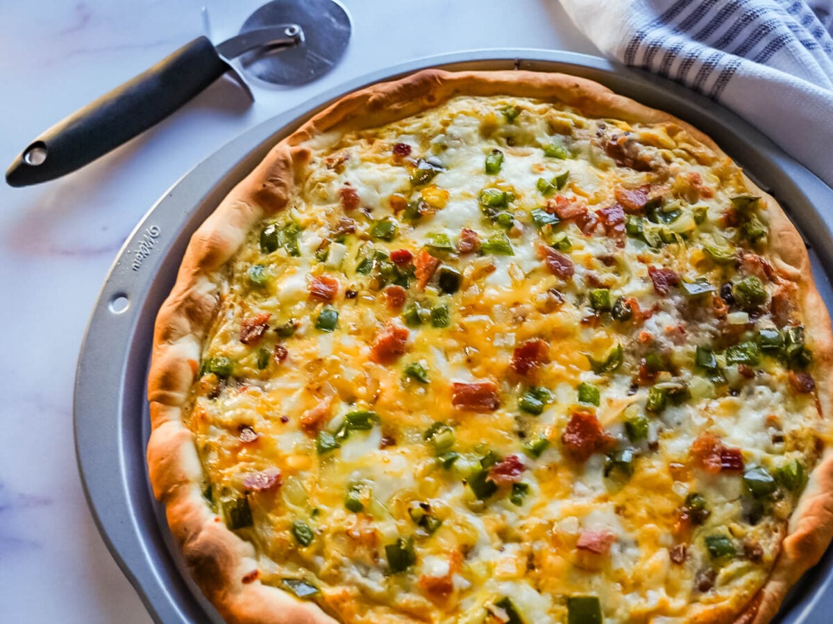 side photo of breakfast pizza next to a pizza cutter
