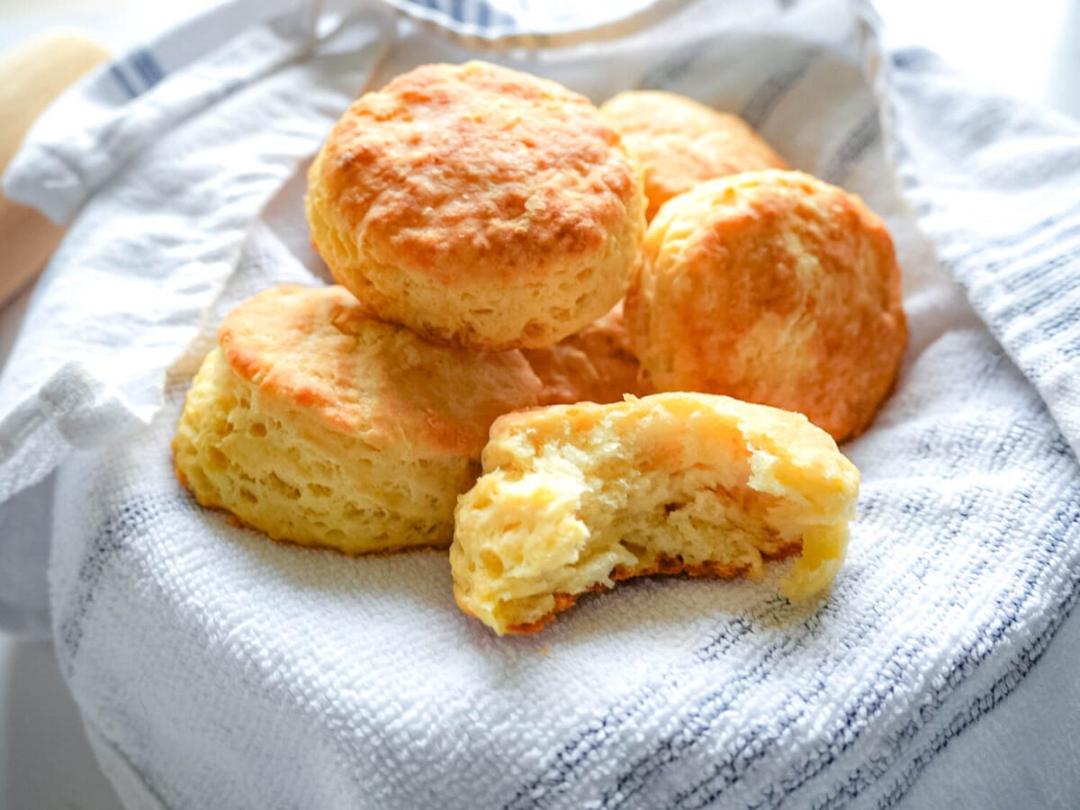 side view photo of buttermilk biscuits with one in the front thats broken to show layers