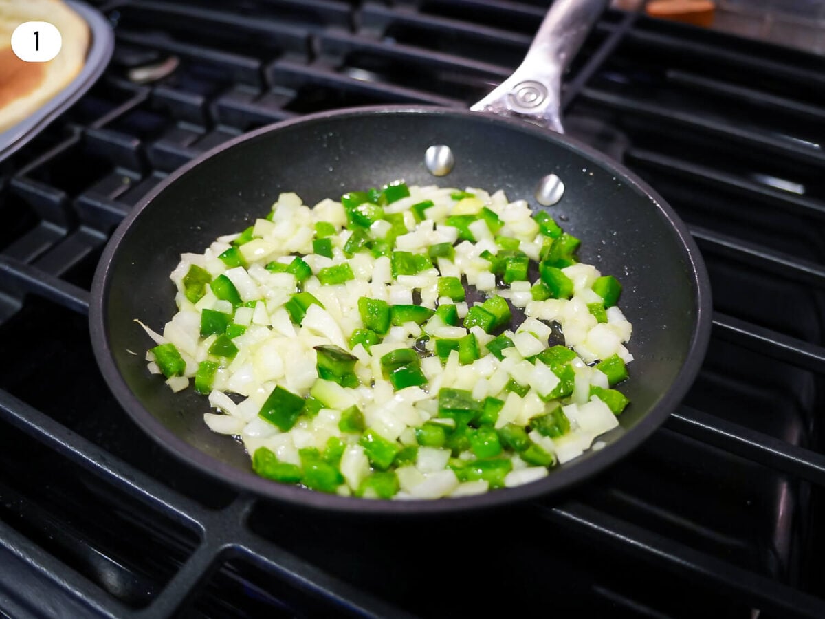 step 1 photo of onions and peppers cooking in a pan