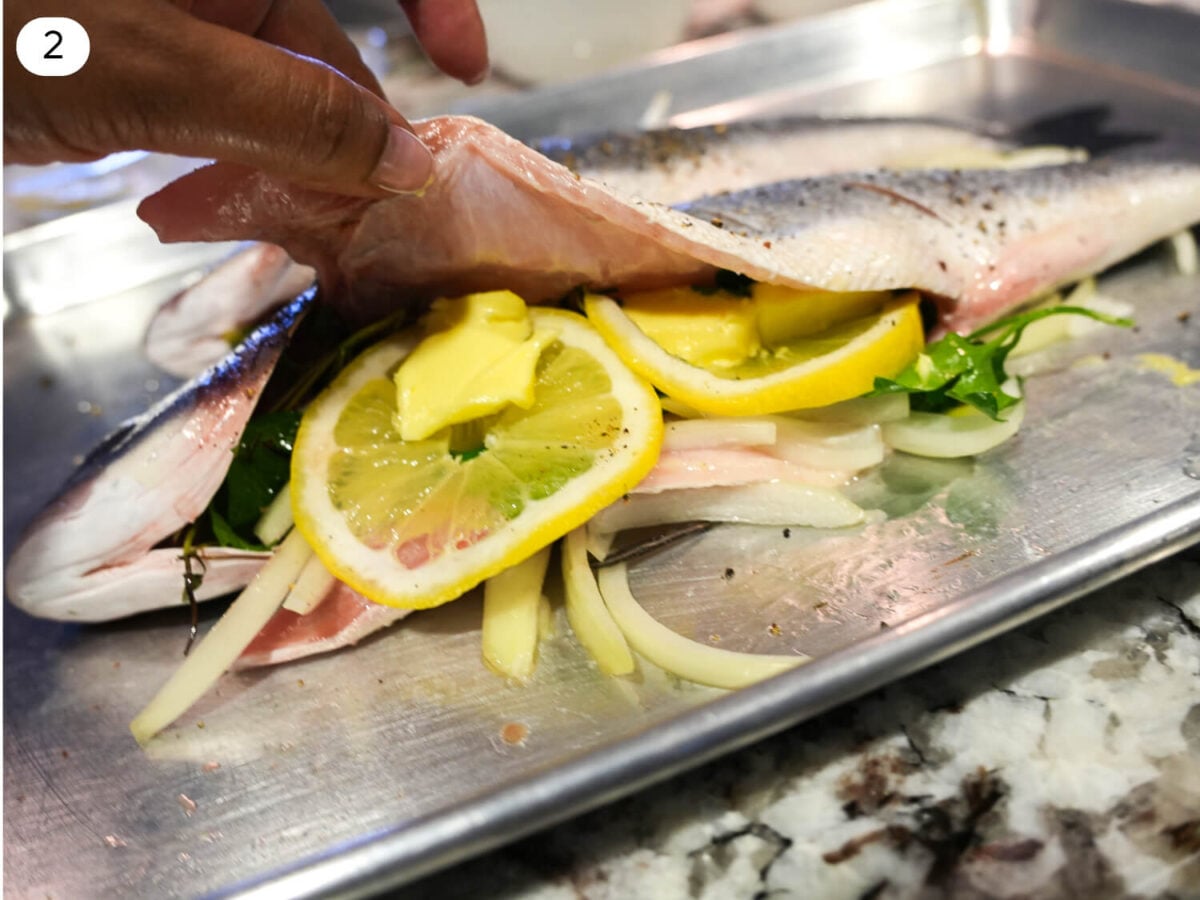 step 2 photo of a seasoned branzino with ingredients inside fish