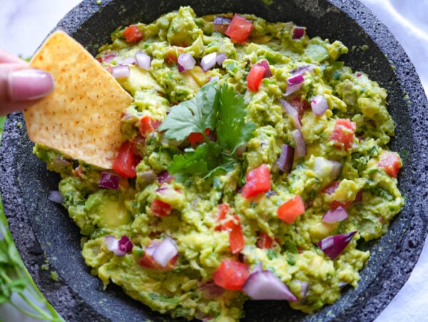 photo showing someone scooping Guacamole with a tortilla chip