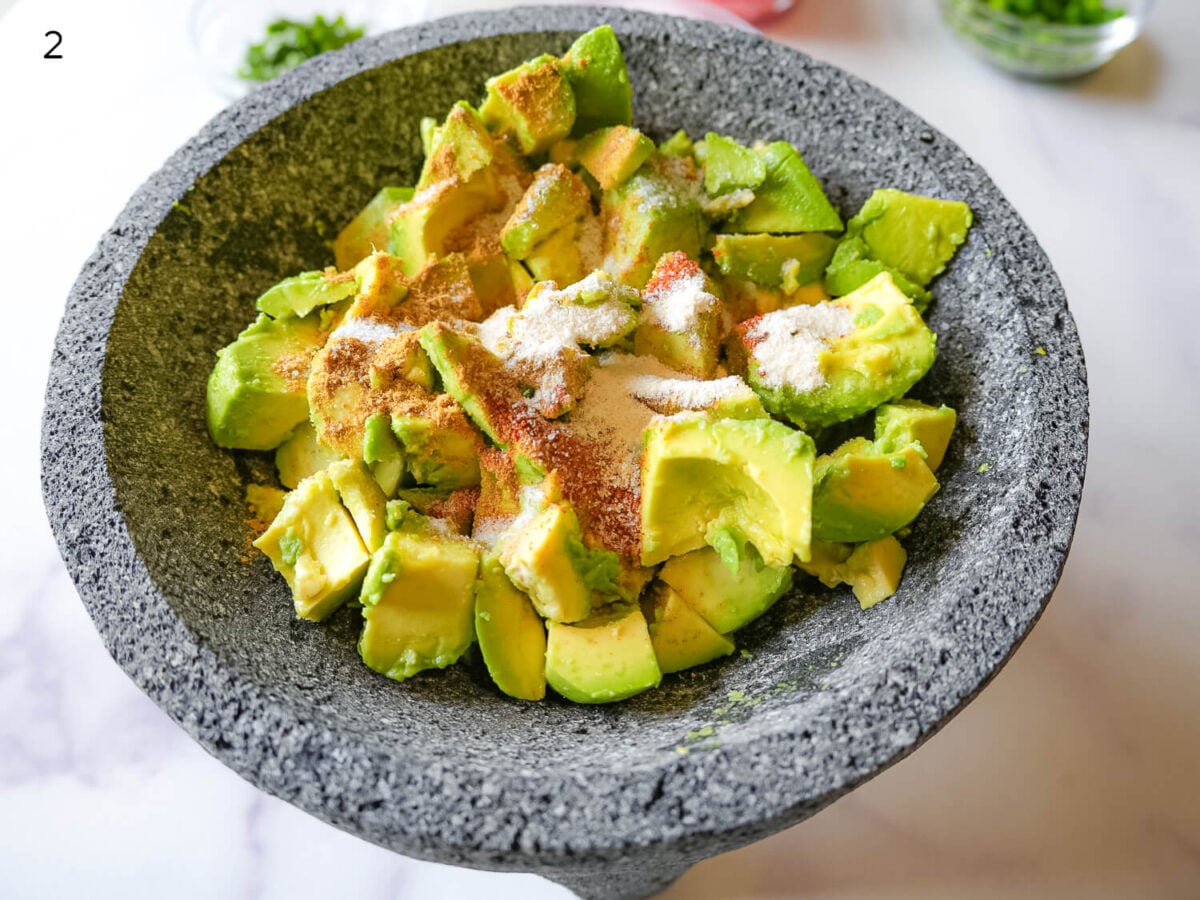 step 2 photo showing seasoning avocados before mashing