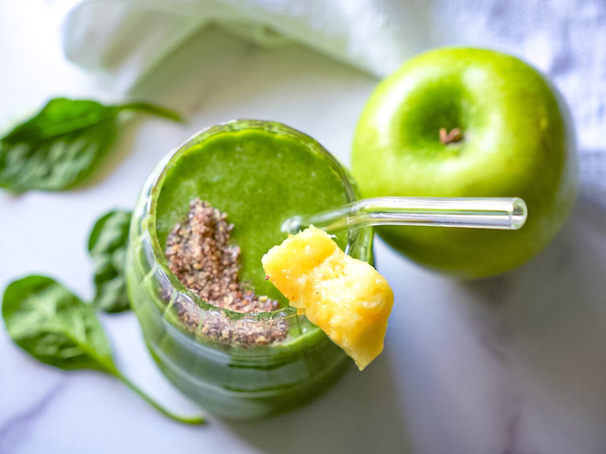 Overhead photo of a Pineapple Spinach Smoothie next to a green apple