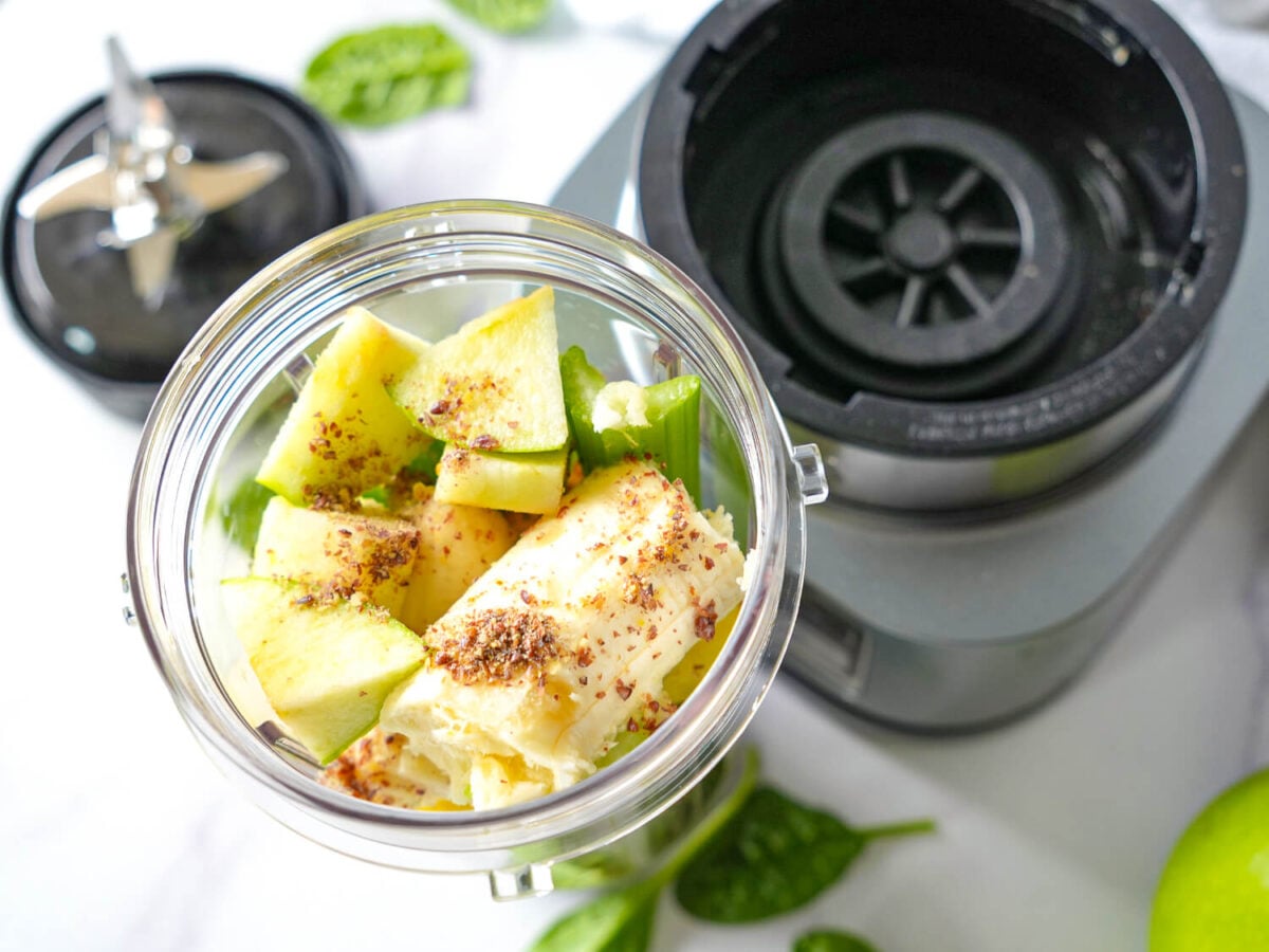 Overhead photo of ingredients in blender cup next to a blender
