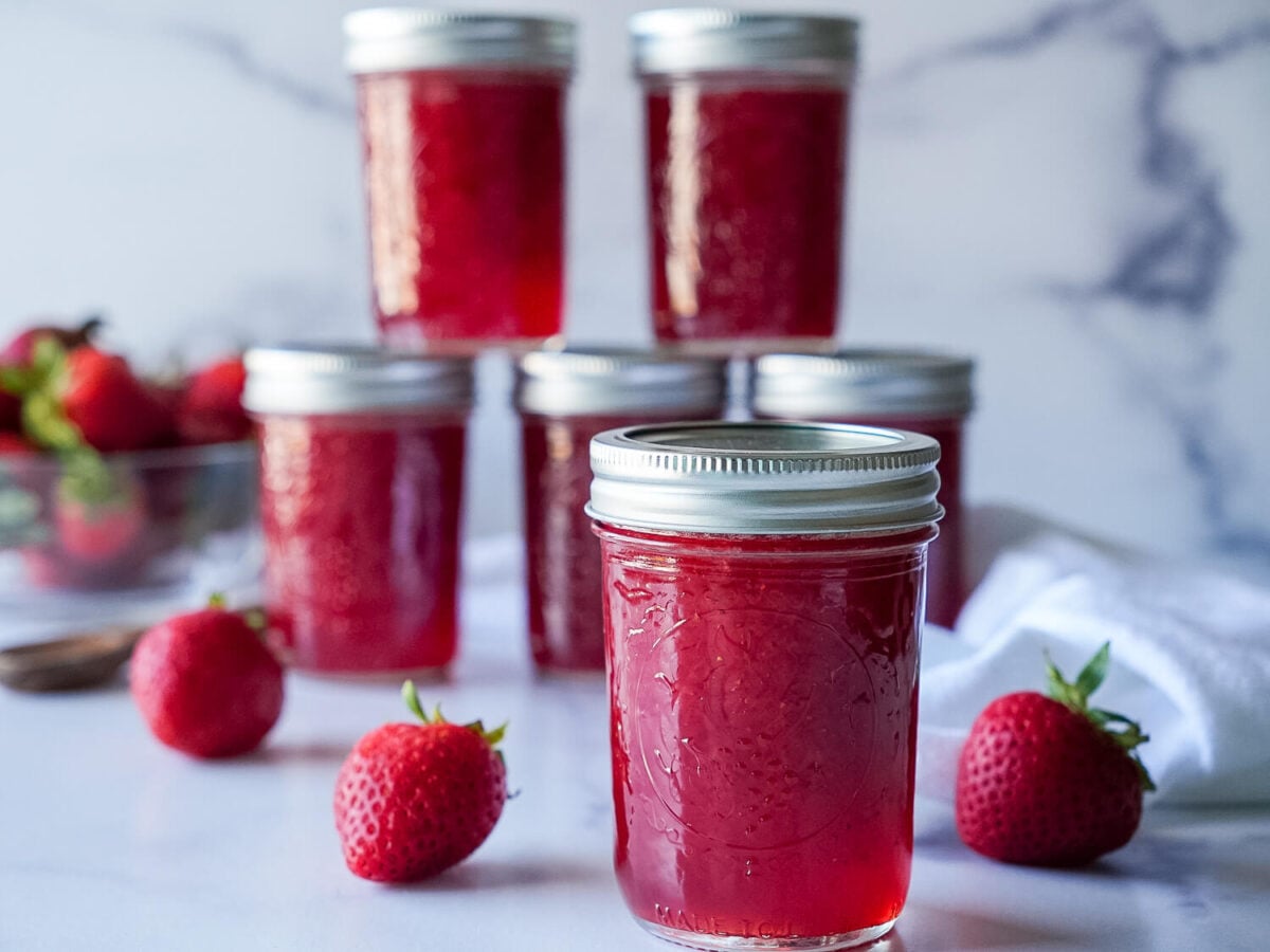 focused photo of strawberry jam in foreground and five in the back