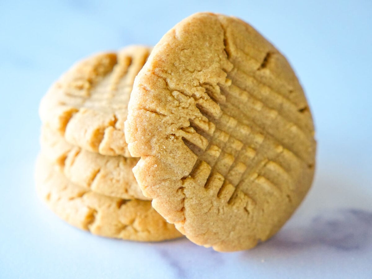 photo of 4 peanut butter cookies stacked on top of each other and one leaning on the side
