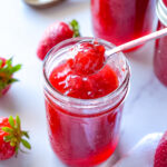 photo of a spoonful of strawberry jam over a mason jar