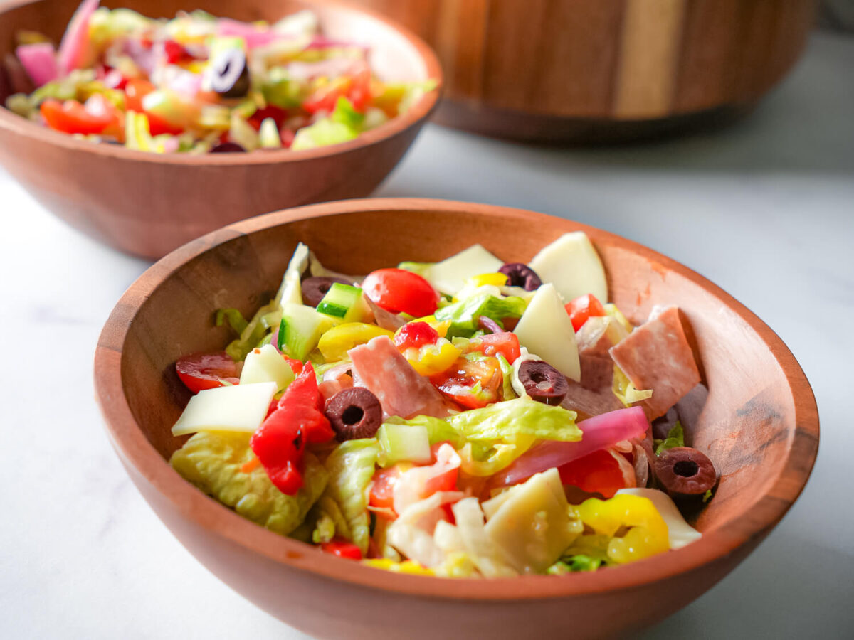 photo of an Italian chopped salad in a bowl with a blurred salad bowl in the background