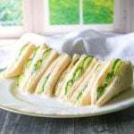 photo of cucumber sandwiches on a plate in front of a window