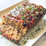 photo of meatloaf on a marble surface on a white plate