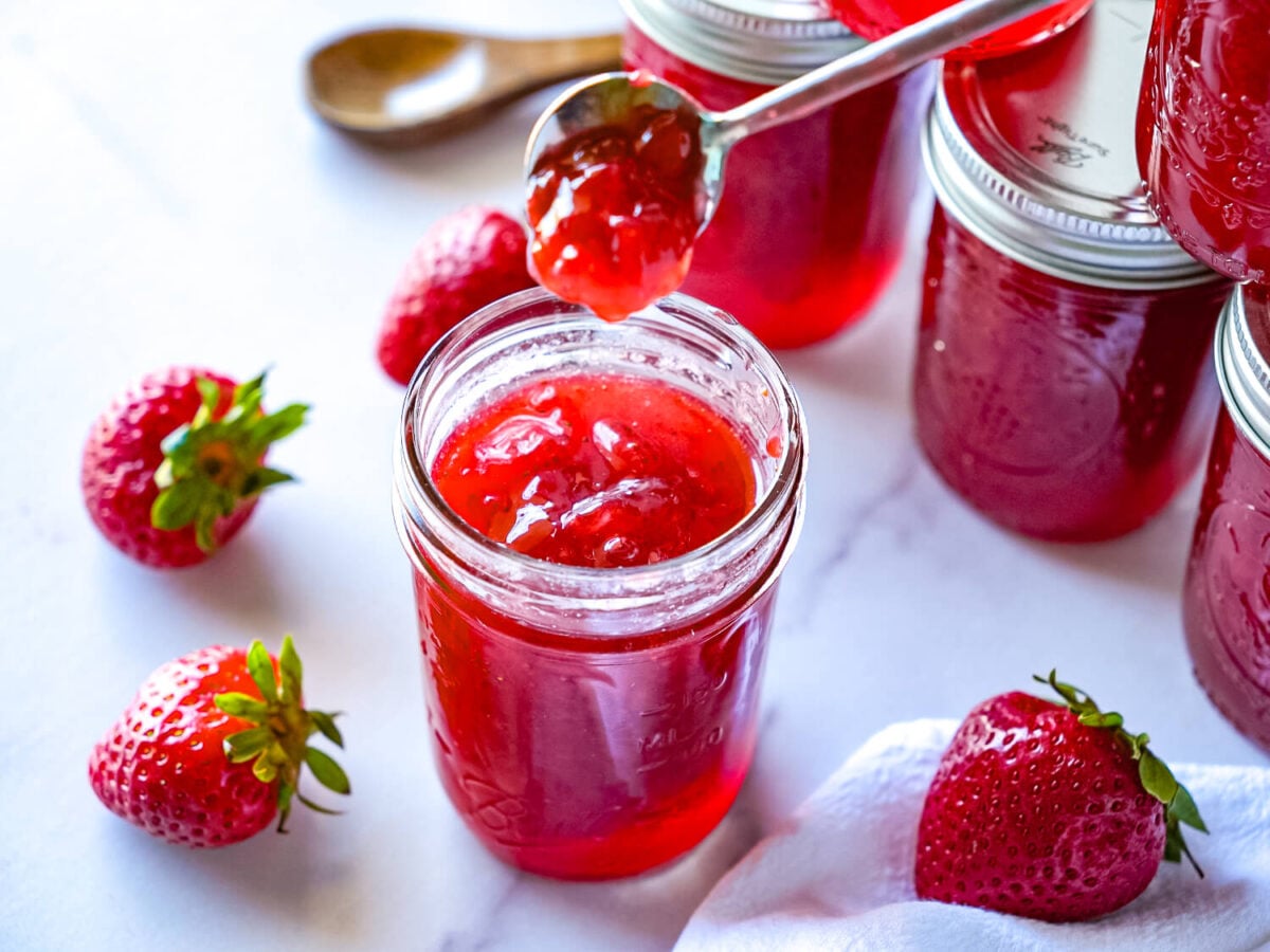 photo of strawberry jam falling into a mason jar