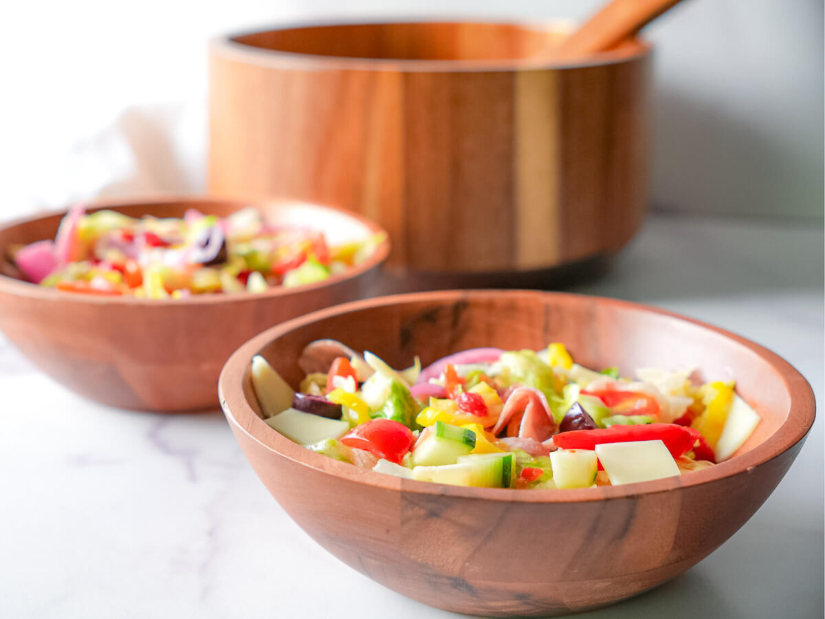 photo of two bowls of Italian chopped salads in front of a serving bowl
