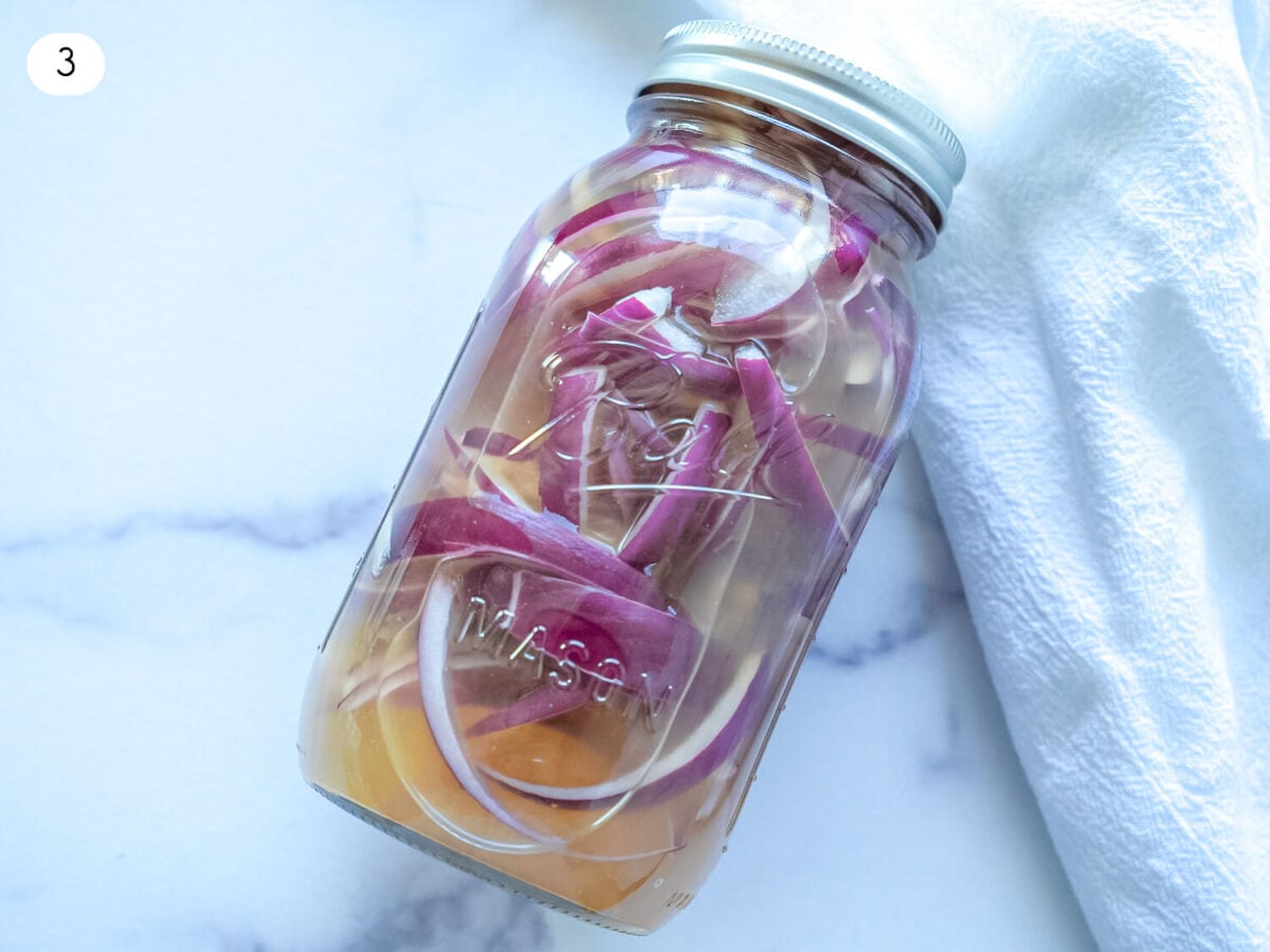 step 3 photo of red onions in pickling solution in a mason jar