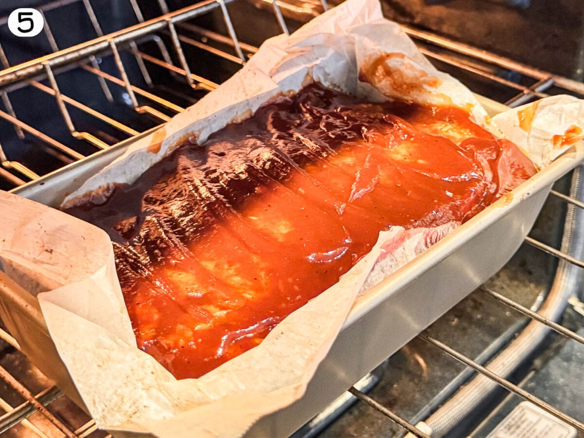 step 5 photo of meatloaf baking in the oven with glaze on top