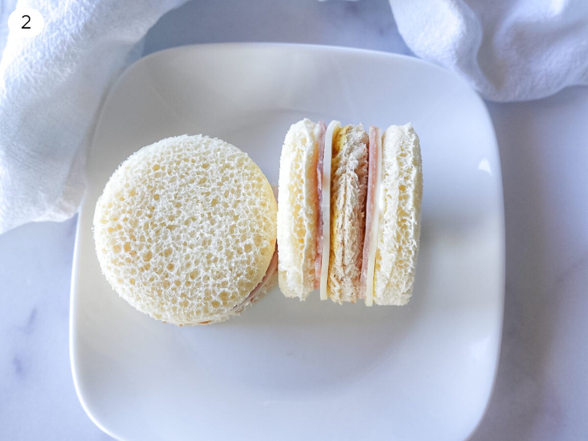 step two photo of Ham & Cheese Tea Sandwiches being put together on a white plate