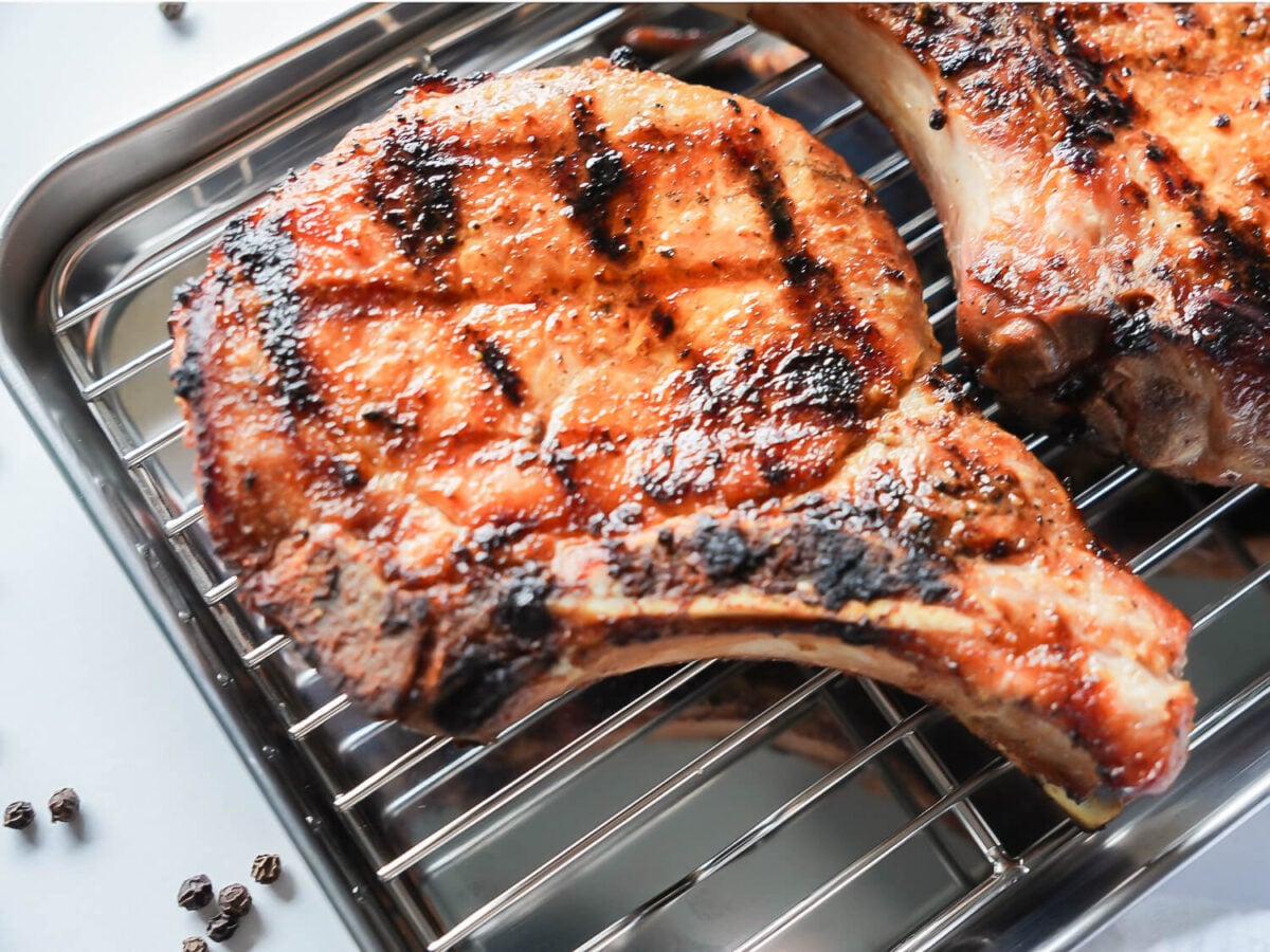 Close up photo of a grilled pork chop with grill marks on a silver tray