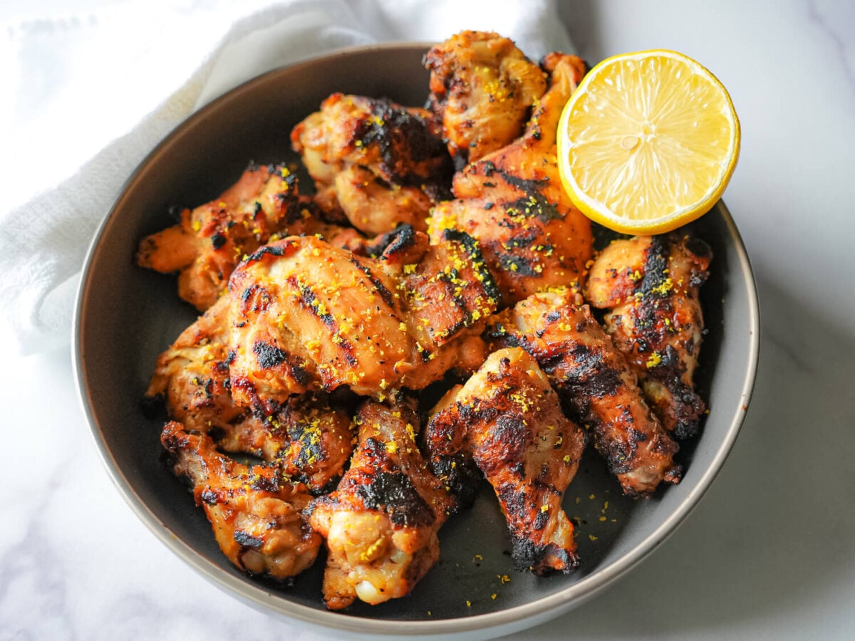 HERO photo of grilled lemon chicken in a bowl with a lemon slice