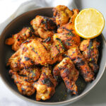 HERO photo of grilled lemon chicken in a bowl with a lemon slice
