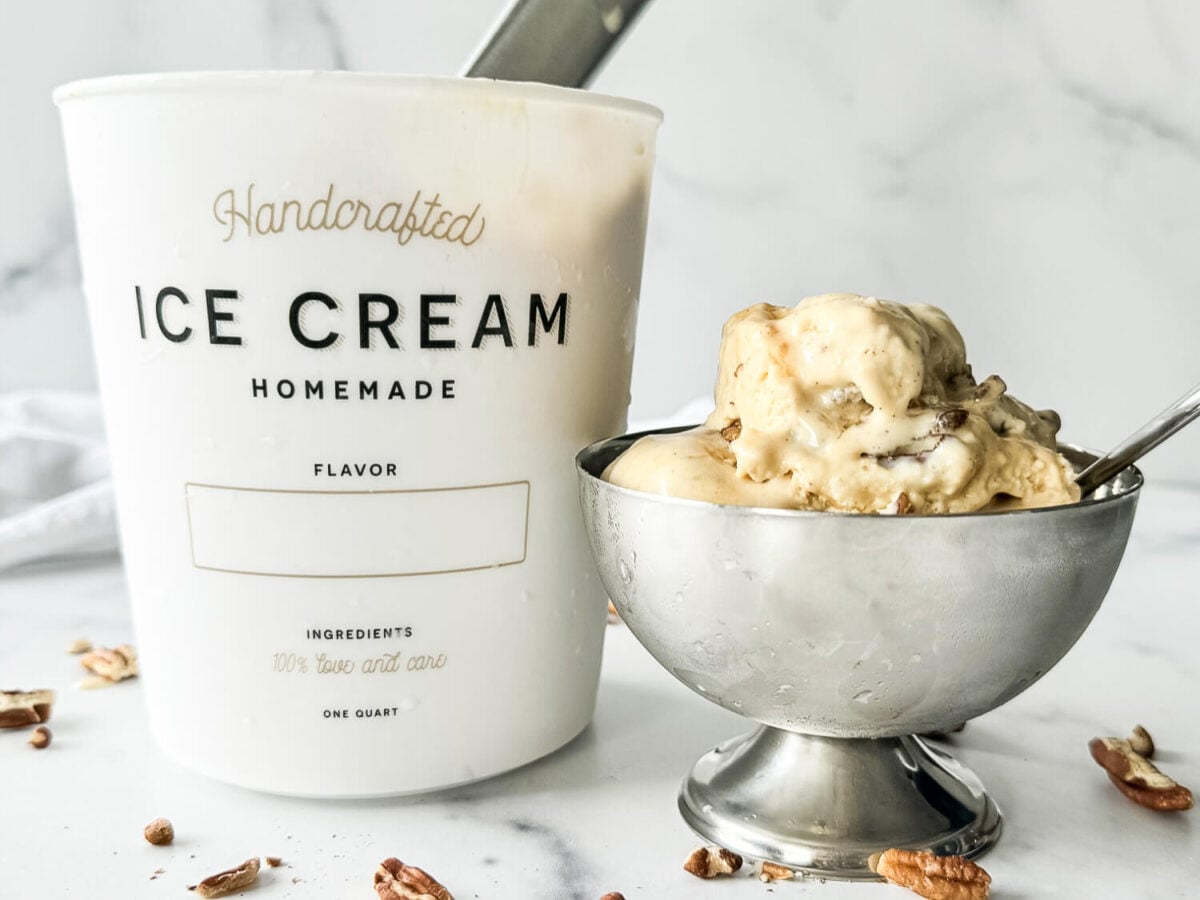 Photo of praline ice cream in a silver bowl next to a tub of ice cream