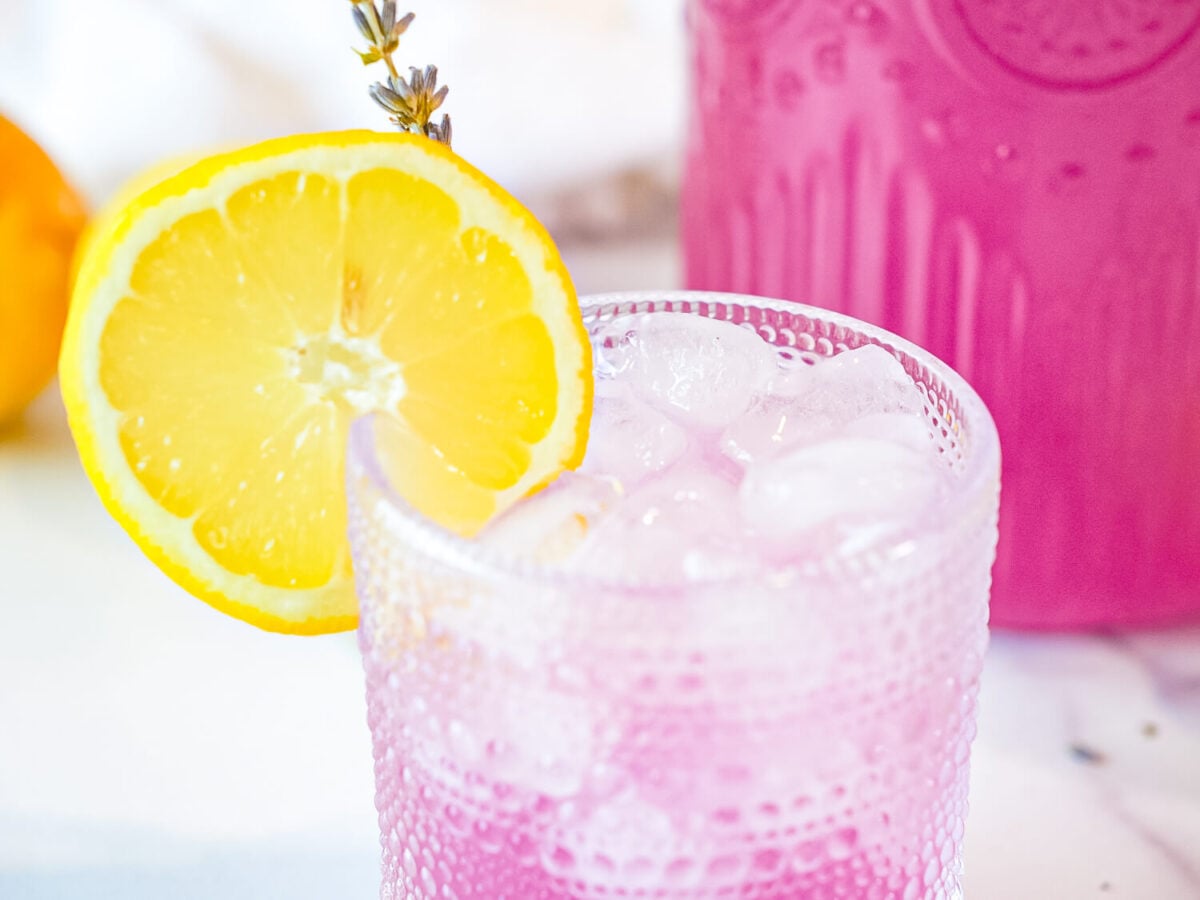 close up photo of lavender lemonade in a glass with a lemon slice garnish