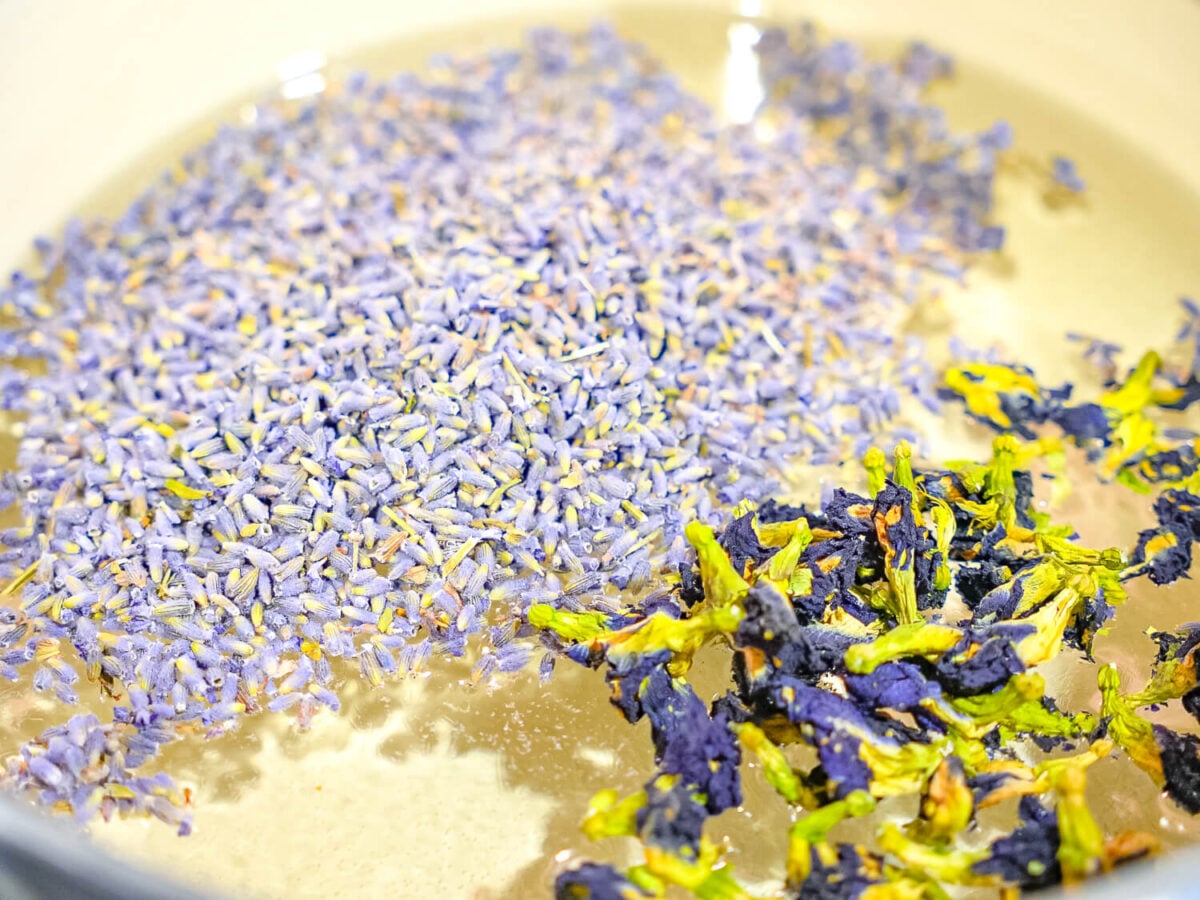 close up photo showing lavender flowers and butterfly pea flowers in simple syrup