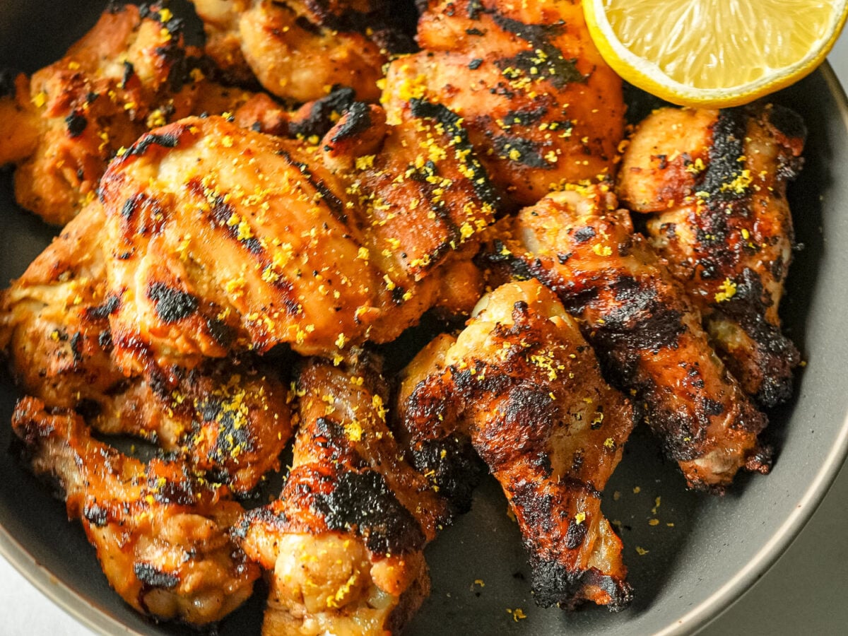 overhead photo of grilled lemon chicken with a lemon slice