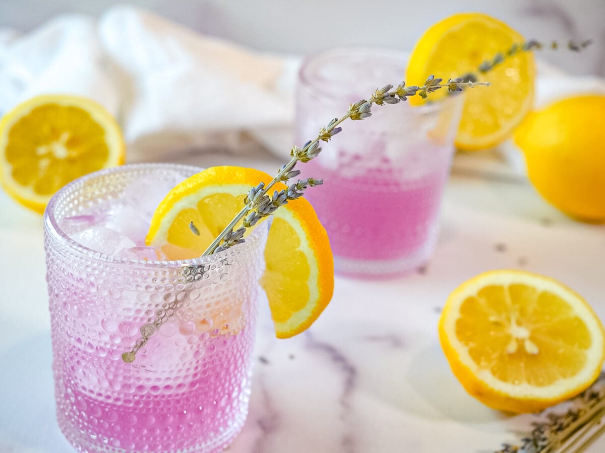 overhead photo of lavender lemonade in two glasses with lemons