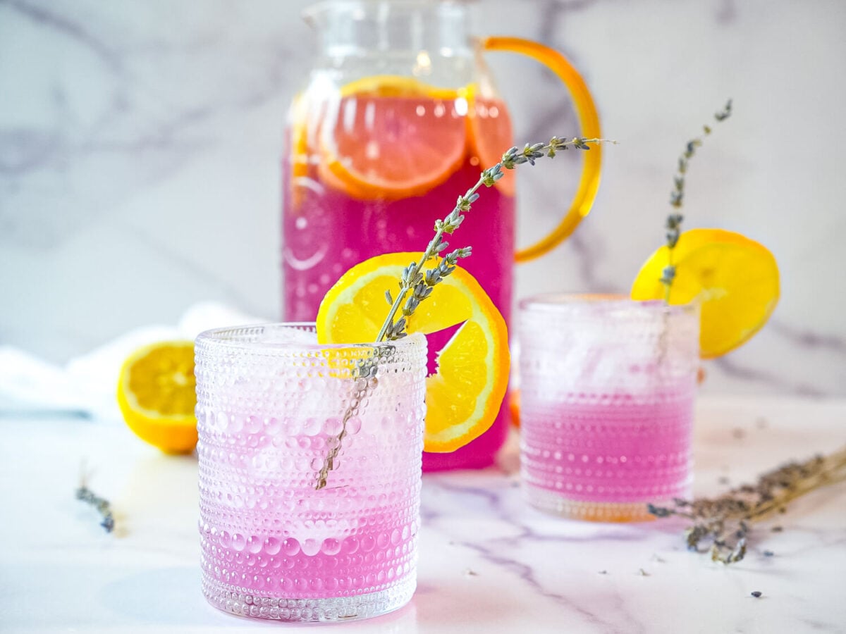 photo of 2 glasses of lavender lemonade with a pitcher of lavender lemonade